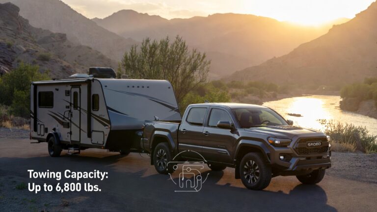 2025 Toyota Tacoma towing a travel trailer by a scenic riverside.
